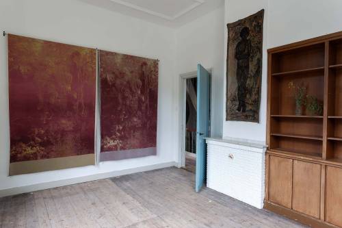 Op de eerste verdieping hangen grote zeefdrukken op textiel 